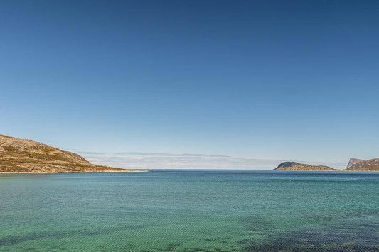 Arktisk havro-sommerøy med klart, turkist hav og åpen horisont under nordnorsk himmel.