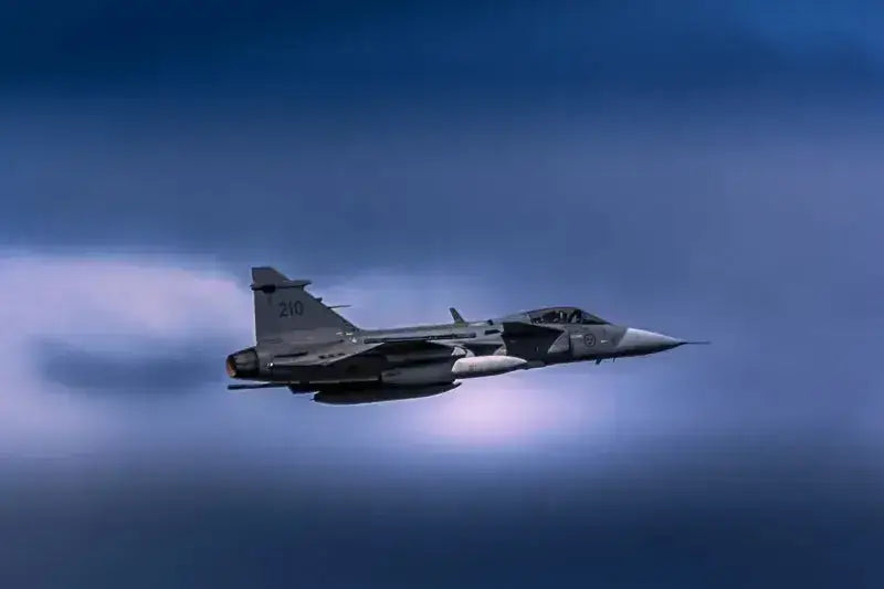 JAS 39 Gripen flyr gjennom dramatisk blågrå himmel, symboliserer kraft og moderne teknologi.