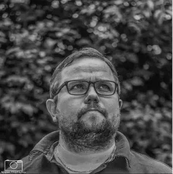 Bilder tatt av fotograf Rolf Petter Skogly, portrett av mann med briller i svart-hvitt.