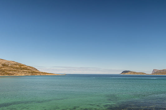 Arktisk havro-sommerøy med klart, turkist hav og åpen horisont under nordnorsk himmel.