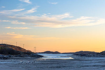 Brønnøysund solnedgang over fjell og hav, med varme toner og skyformasjoner.