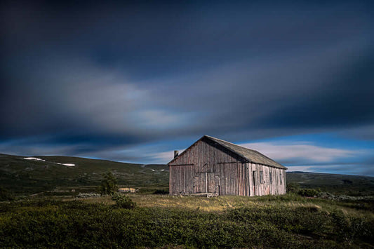Den gamle fjellstua i Saltfjellet, omgitt av høyfjellsnatur og dramatisk himmel.