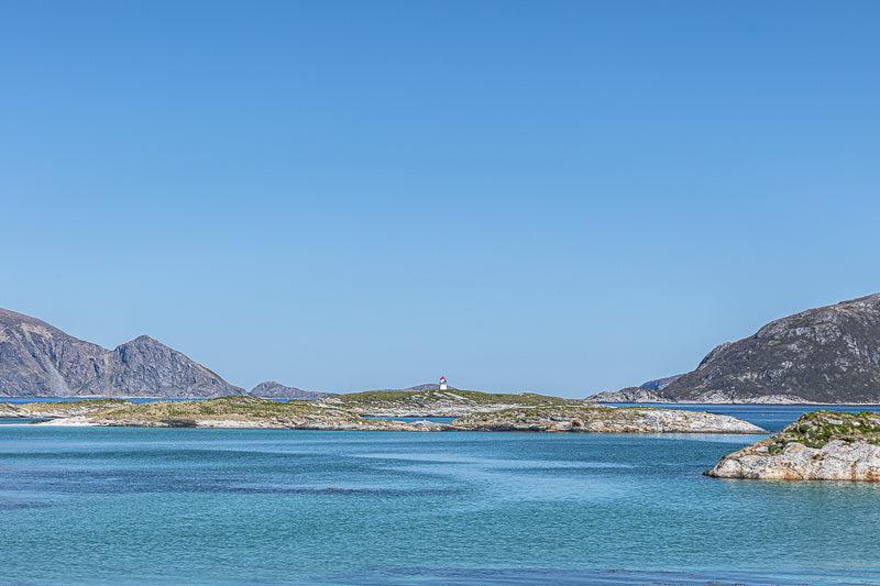 Fyrlyset ved Sommerøy med klart blått hav og små holmer i Nord-Norge, som representerer kystnatur.