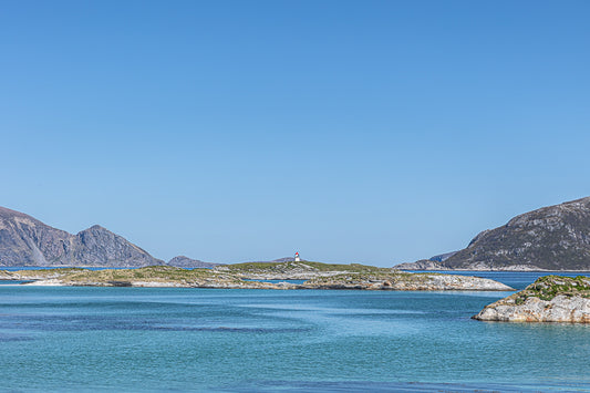 Fyrlyset ved Sommerøy med klart blått hav og små holmer i Nord-Norge, som representerer kystnatur.