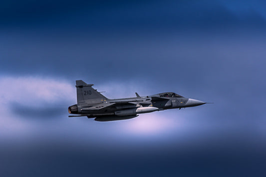 JAS 39 Gripen flyr gjennom dramatisk blågrå himmel, symboliserer kraft og moderne teknologi.