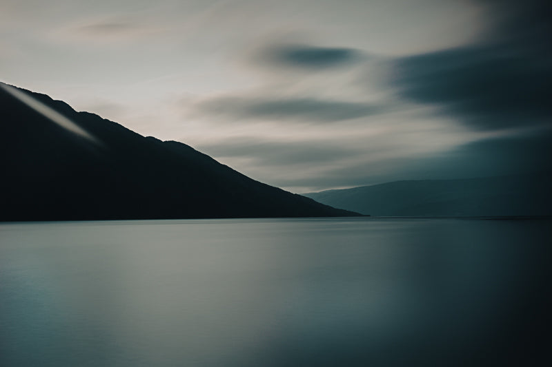 Stillhet over Vefsnfjorden med silkemykt vann og dramatiske skyer i en minimalistisk landskapsfotografi.