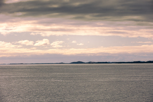 Stillhet over Altenfjorden med åpent hav, lav horisont og myke toner i himmelen.
