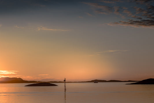 Kveldslys av stille hav og lavholmer i gyllent lys fra Tonnes på Helgelandskysten