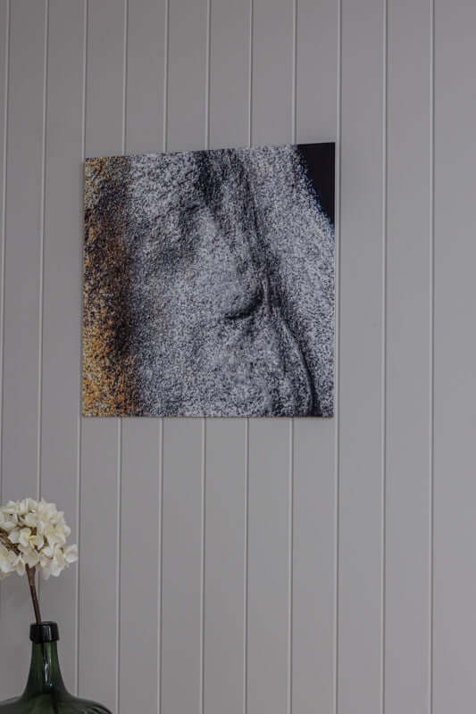 Stoneface minimalistisk steinkunst med gulltoner og grå struktur på veggen.