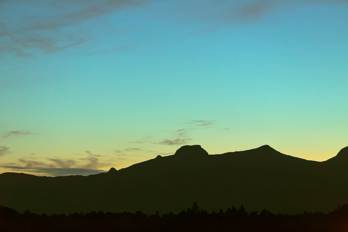 Skumringslys i Utskarpen, mørke fjellsilhuetter mot en rolig himmel i skumringen.