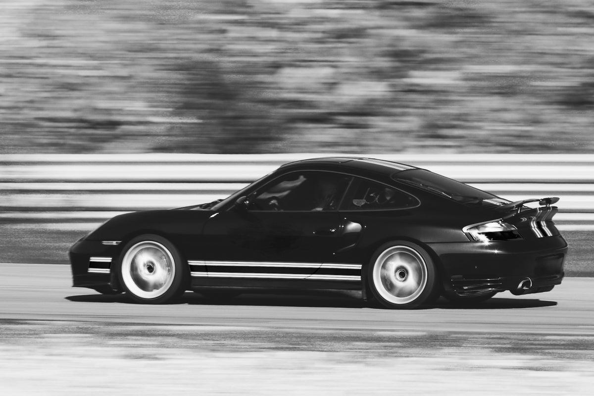 Porsche i høy fart, sort-hvitt veggbilde med rå kjøreglede og dynamisk bevegelse.