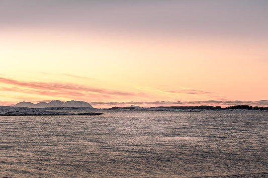 Vegafjellan sett fra Herøy med kveldslys over havet og fjell i bakgrunnen.